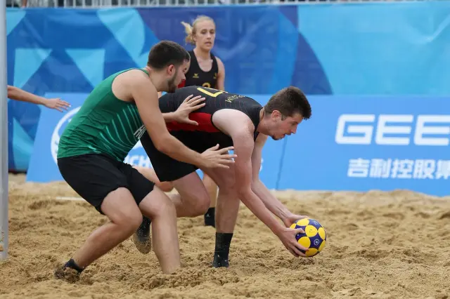 Players reach for the ball in the sand